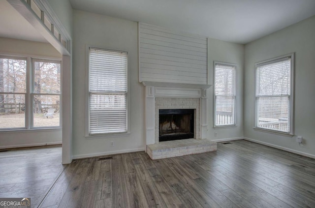 unfurnished living room with hardwood / wood-style floors, a fireplace, and a healthy amount of sunlight