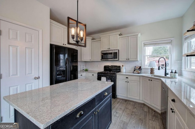 kitchen with sink, white cabinetry, black appliances, a kitchen island, and decorative light fixtures