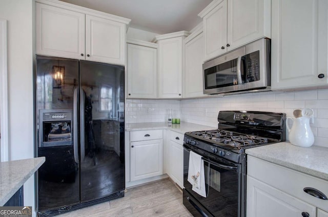 kitchen featuring light stone counters, tasteful backsplash, black appliances, and white cabinets