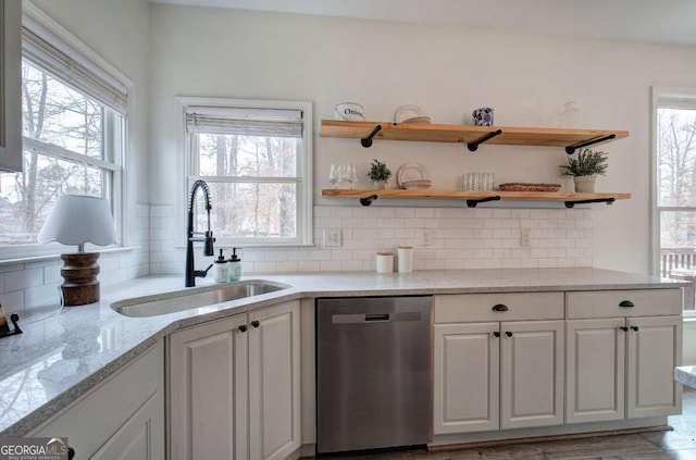 kitchen featuring sink, white cabinetry, tasteful backsplash, stainless steel dishwasher, and light stone countertops