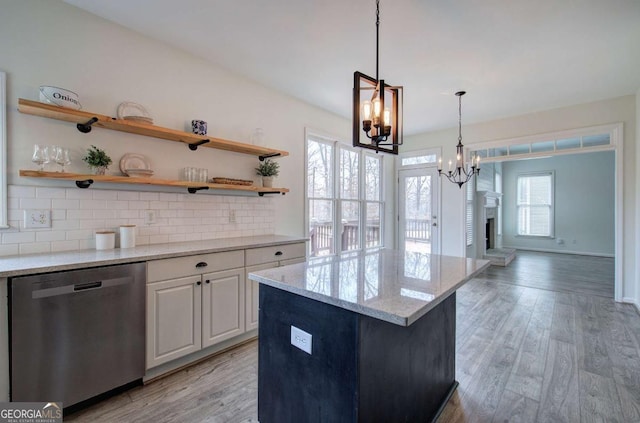 kitchen with tasteful backsplash, white cabinetry, dishwasher, light hardwood / wood-style floors, and light stone countertops