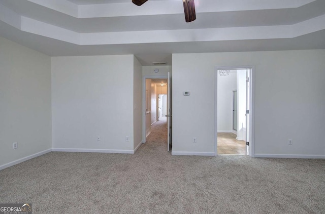 carpeted spare room with a tray ceiling