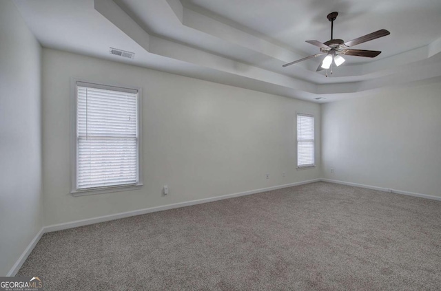 carpeted spare room with a tray ceiling and ceiling fan