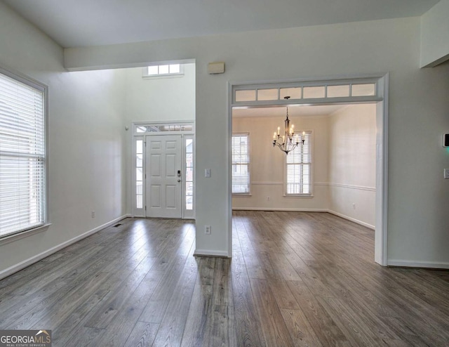 entryway featuring dark wood-type flooring and a chandelier