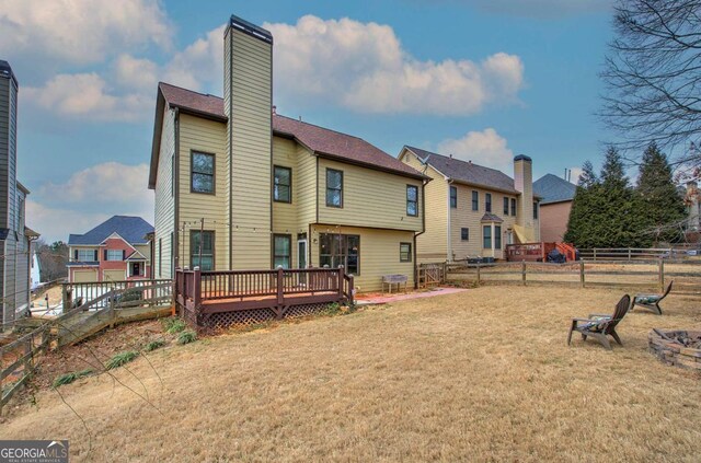 rear view of house featuring a wooden deck and a yard