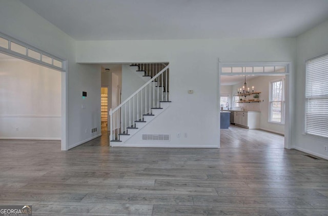 spare room featuring wood-type flooring and a chandelier