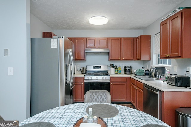 kitchen with appliances with stainless steel finishes, sink, and a textured ceiling