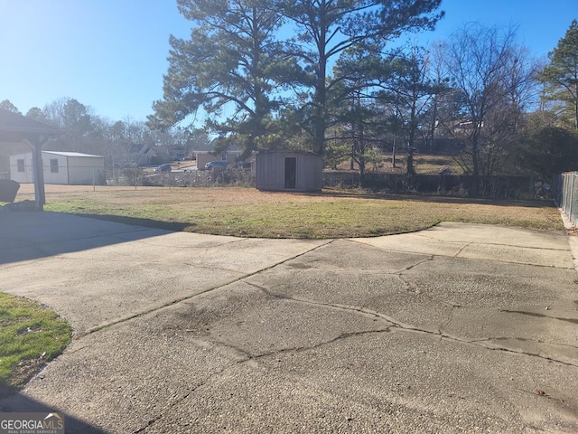 view of yard with an outbuilding, a storage unit, and fence