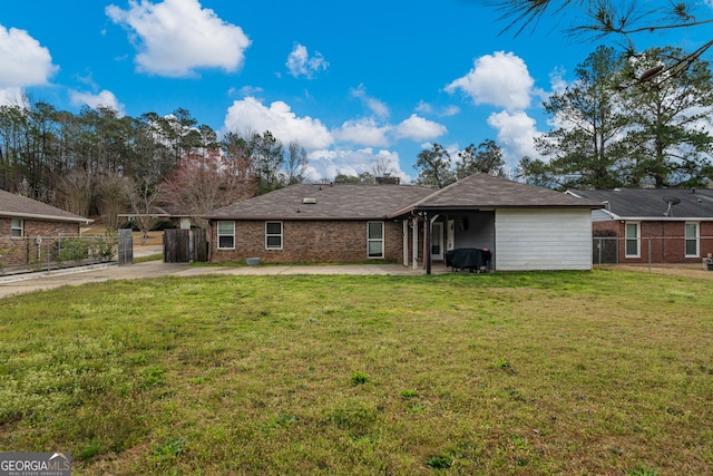 rear view of property with brick siding, fence, a lawn, and a patio