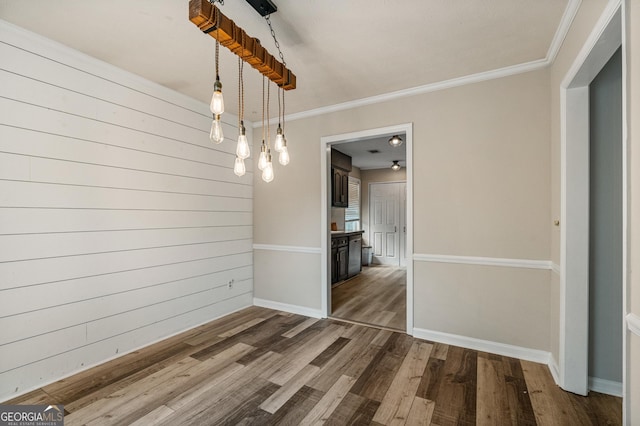 unfurnished dining area with baseboards, ornamental molding, and dark wood-type flooring