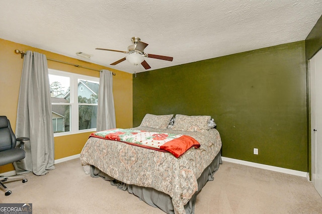 bedroom with a textured ceiling, light colored carpet, and ceiling fan