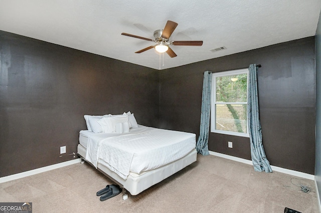 bedroom featuring light carpet, a textured ceiling, and ceiling fan