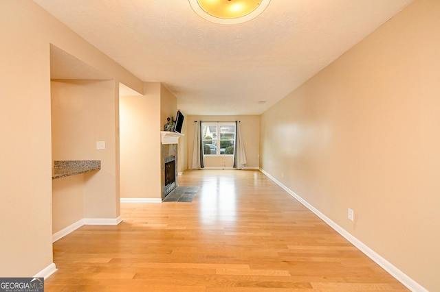 unfurnished living room featuring a tiled fireplace and light hardwood / wood-style floors