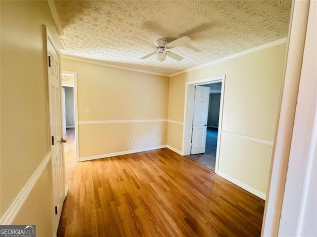 spare room featuring hardwood / wood-style flooring, ornamental molding, a textured ceiling, and ceiling fan