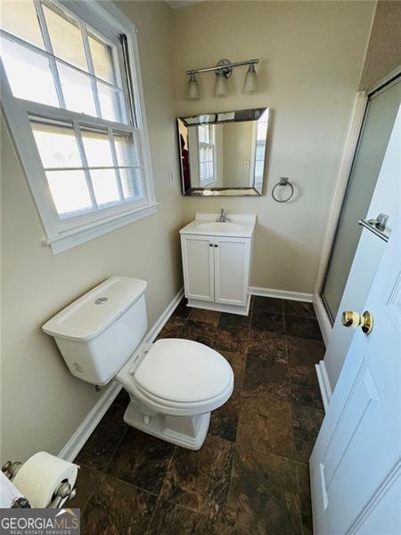 bathroom featuring a shower with door, vanity, and toilet