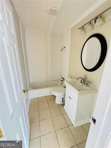 full bathroom with tile patterned floors, toilet, vanity, and a textured ceiling