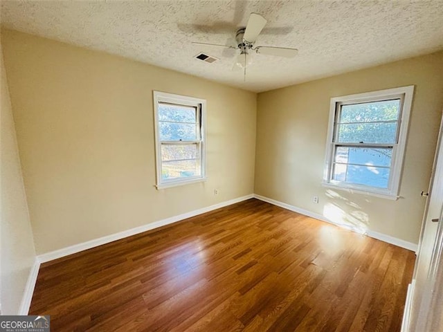 empty room with a textured ceiling, wood-type flooring, and ceiling fan