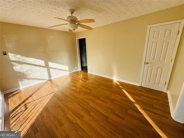 spare room featuring dark wood-type flooring, ceiling fan, and a textured ceiling