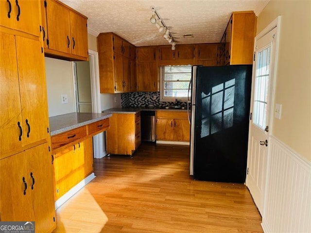 kitchen featuring stainless steel appliances, track lighting, a textured ceiling, decorative backsplash, and light wood-type flooring