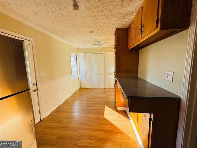 corridor featuring ornamental molding, a textured ceiling, and light hardwood / wood-style floors