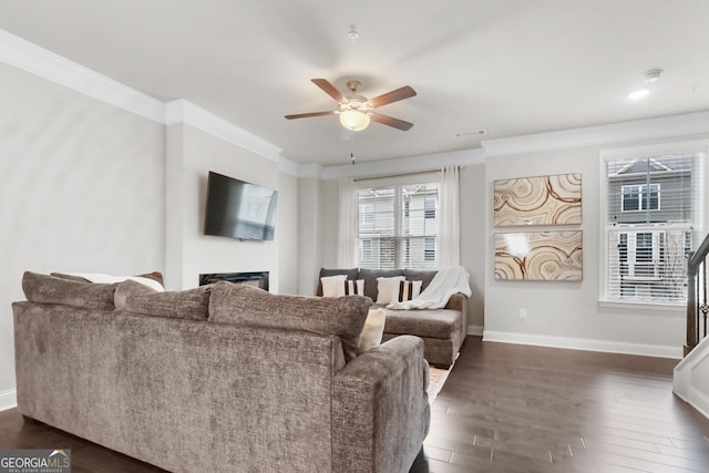 living room featuring dark wood-type flooring, ornamental molding, and ceiling fan