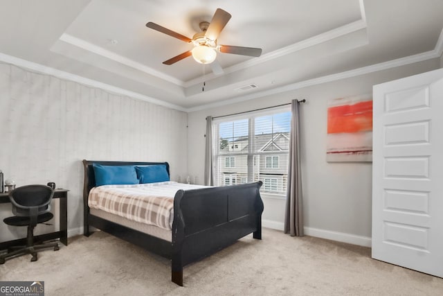 bedroom featuring ceiling fan, ornamental molding, a tray ceiling, and light carpet