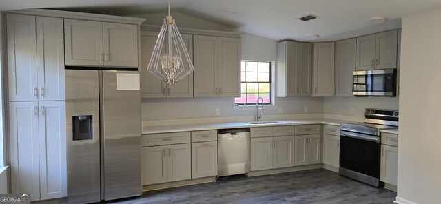 kitchen with lofted ceiling, stainless steel appliances, dark hardwood / wood-style floors, and hanging light fixtures