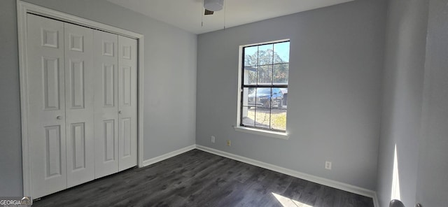 unfurnished bedroom featuring dark wood-style floors, ceiling fan, a closet, and baseboards