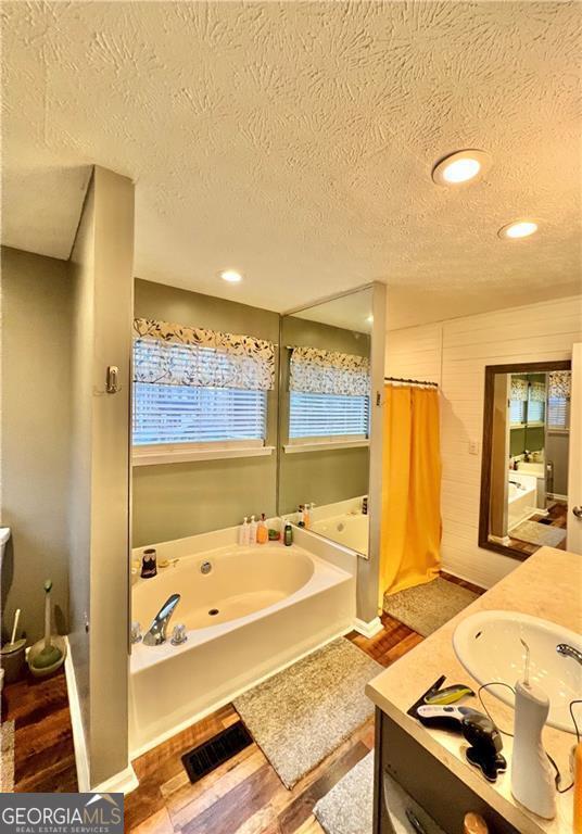 bathroom with vanity, hardwood / wood-style floors, shower with separate bathtub, and a textured ceiling