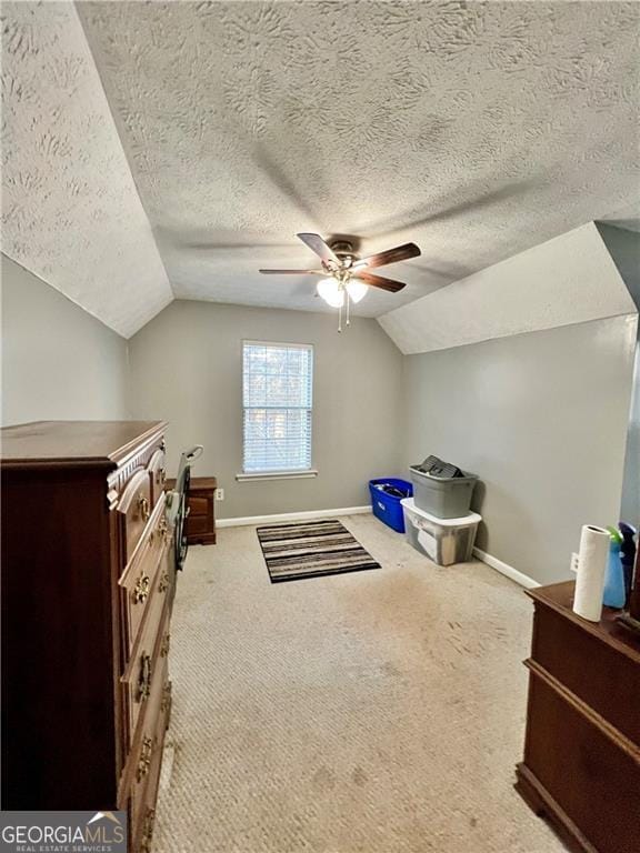 additional living space featuring lofted ceiling, ceiling fan, light colored carpet, and a textured ceiling