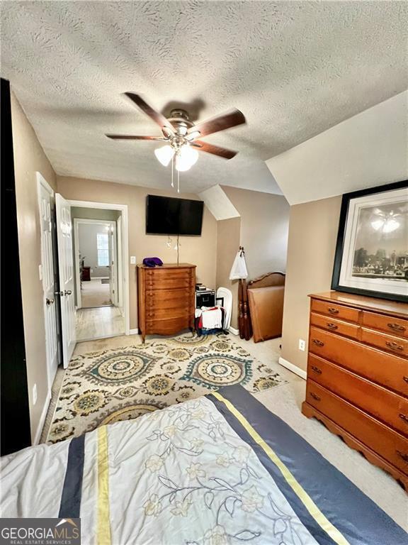 bedroom featuring ceiling fan, lofted ceiling, and a textured ceiling