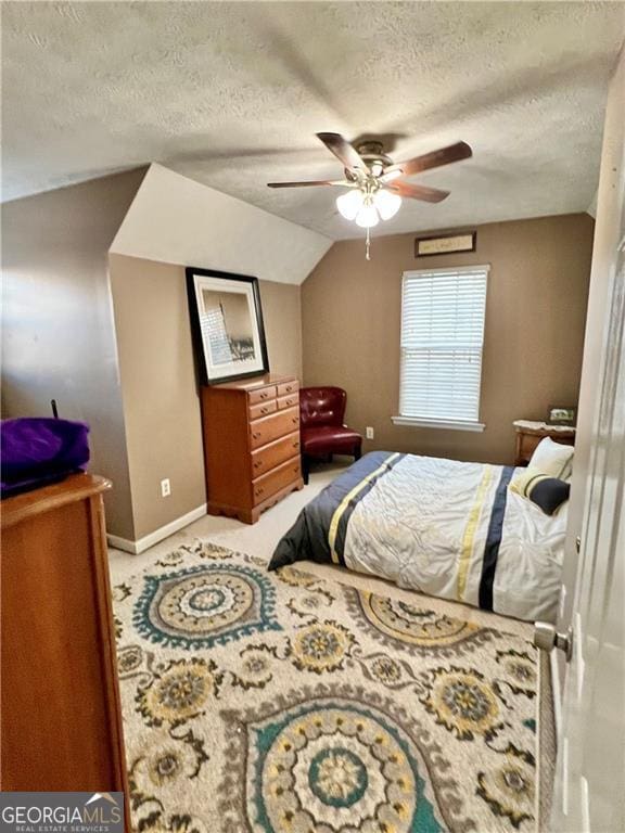 bedroom featuring a textured ceiling, vaulted ceiling, and ceiling fan