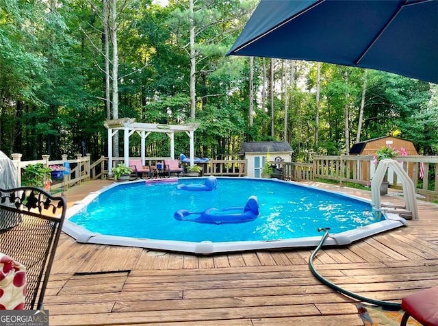 view of pool with a pergola, a deck, and a storage unit