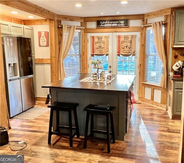 kitchen with a kitchen island, light hardwood / wood-style flooring, a kitchen bar, and stainless steel fridge with ice dispenser