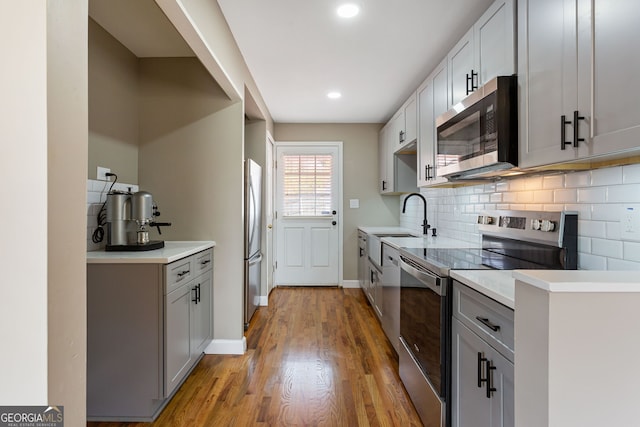 kitchen featuring gray cabinetry, sink, light hardwood / wood-style flooring, and stainless steel appliances