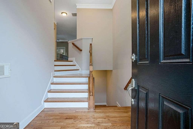 stairway with hardwood / wood-style floors and crown molding