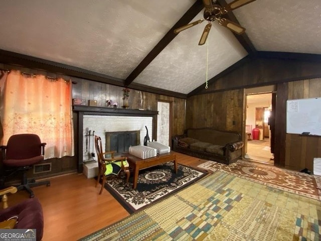 living room with vaulted ceiling with beams, light hardwood / wood-style floors, a brick fireplace, and wood walls