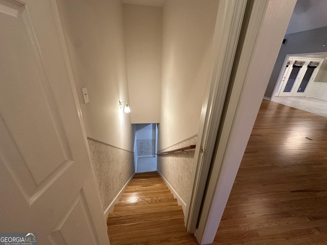 staircase featuring wood finished floors and wainscoting