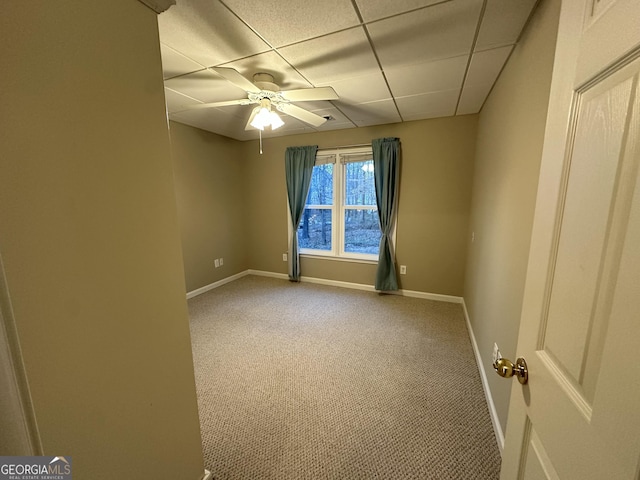 unfurnished room featuring ceiling fan, carpet floors, a paneled ceiling, and baseboards