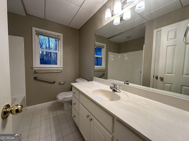 bathroom with baseboards, toilet, tile patterned flooring, vanity, and a paneled ceiling