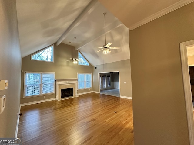 unfurnished living room featuring ceiling fan, a fireplace, wood finished floors, baseboards, and beamed ceiling