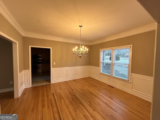 unfurnished dining area with crown molding, a notable chandelier, visible vents, wainscoting, and wood finished floors