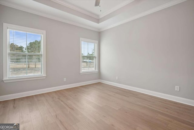 unfurnished room featuring ceiling fan, ornamental molding, a tray ceiling, and light wood-type flooring