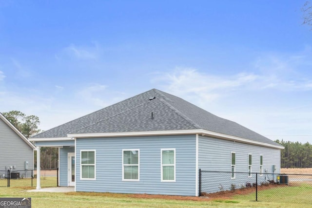 rear view of house featuring central AC and a lawn