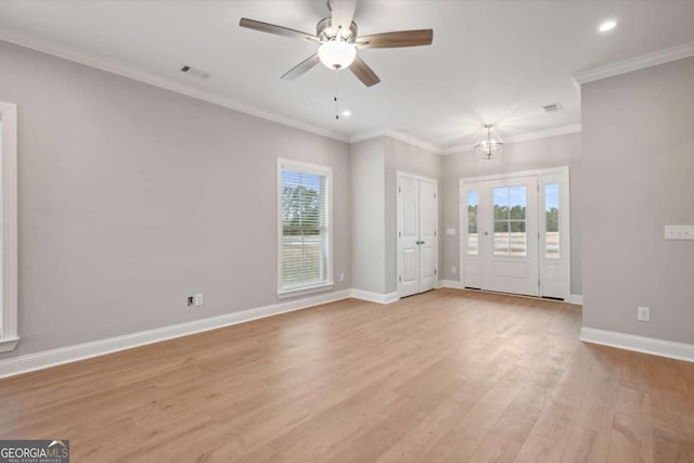 unfurnished living room featuring crown molding, ceiling fan with notable chandelier, and light hardwood / wood-style floors