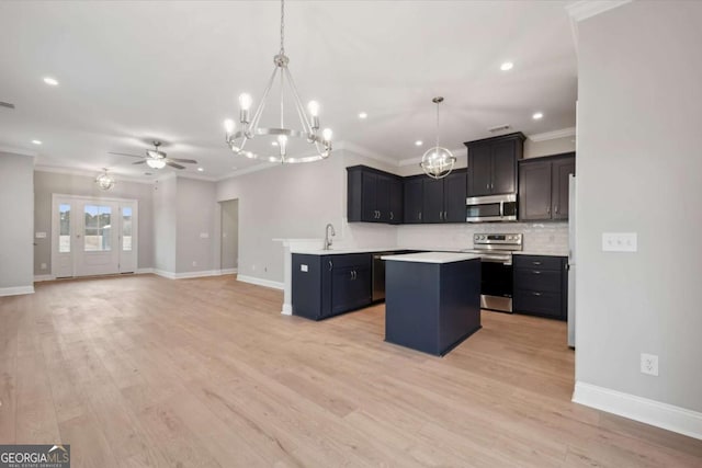 kitchen with a kitchen island, appliances with stainless steel finishes, sink, and an inviting chandelier