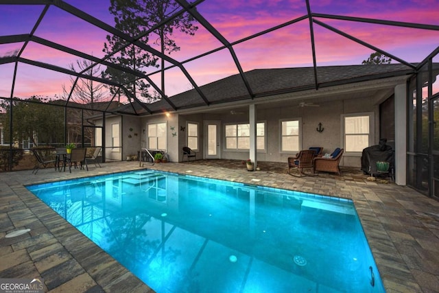 pool at dusk featuring ceiling fan, a lanai, area for grilling, and a patio area