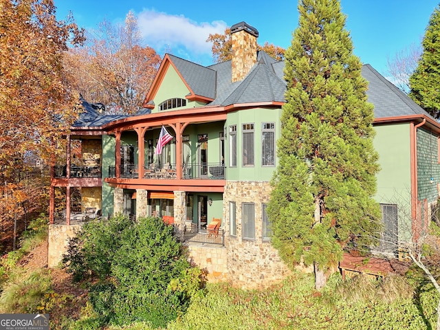 rear view of property featuring a balcony and a patio area