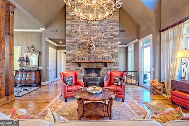 living room with ornamental molding, a stone fireplace, high vaulted ceiling, and light hardwood / wood-style flooring