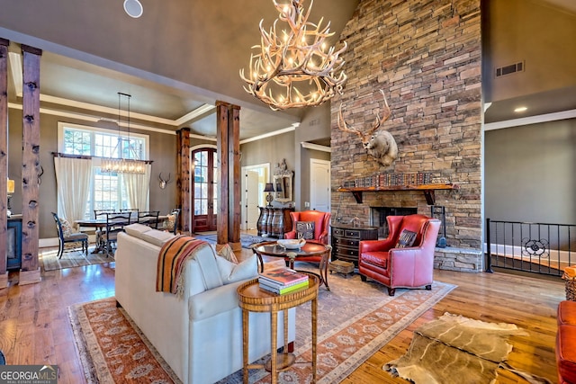 living room with hardwood / wood-style flooring, ornate columns, a high ceiling, and a notable chandelier